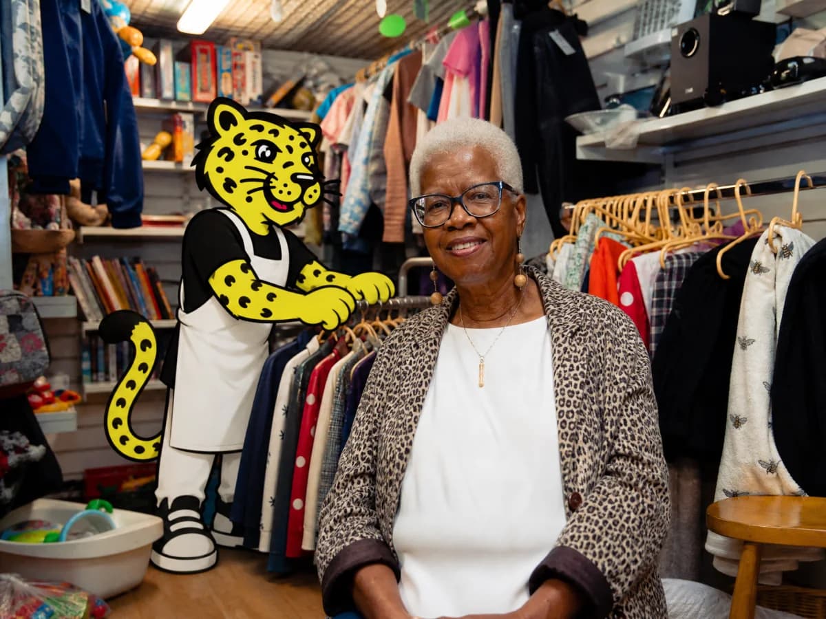 Retail owner beside Leo arranging clothes on a rack