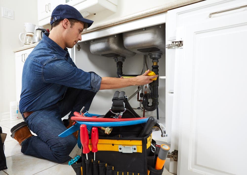 Plumber working under a sink